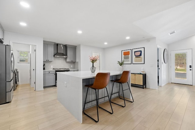 kitchen featuring stainless steel appliances, gray cabinetry, backsplash, visible vents, and wall chimney exhaust hood