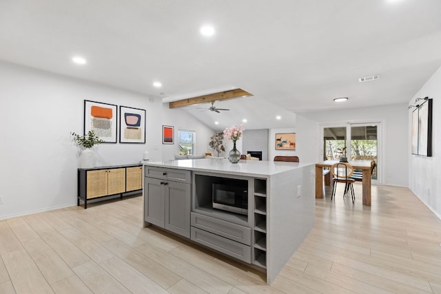 kitchen featuring light countertops, light wood-type flooring, gray cabinets, lofted ceiling with beams, and visible vents
