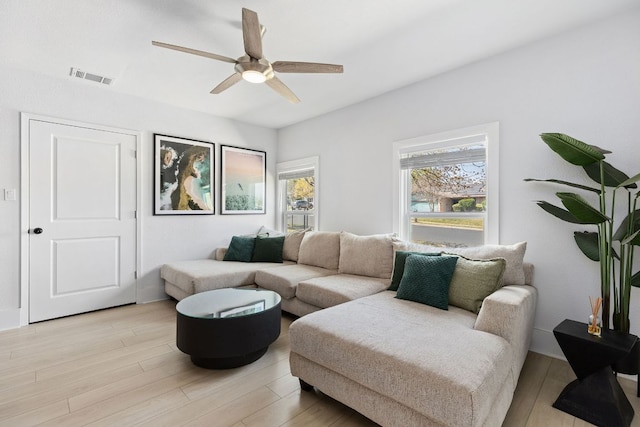 living room with light wood finished floors, visible vents, and ceiling fan