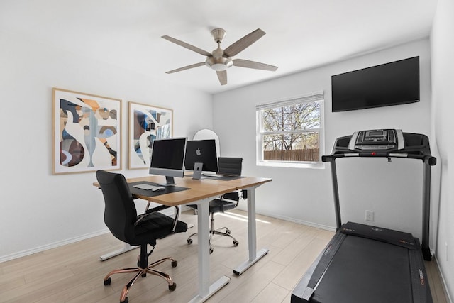 office area with a ceiling fan, baseboards, and light wood-type flooring