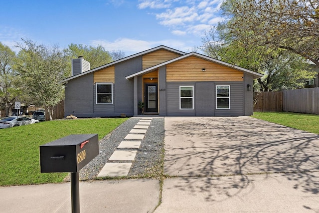 view of front of property featuring a chimney, fence, a front lawn, and concrete driveway