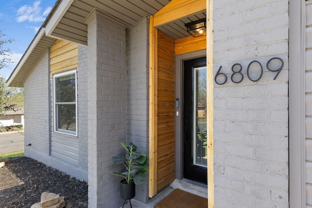 view of exterior entry featuring brick siding