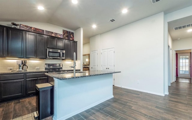 20700 Deep Crk, Lago Vista, TX 78645 - kitchen featuring stainless steel microwave, dark wood-style floors, an island with sink, dark stone counters, and tasteful backsplash