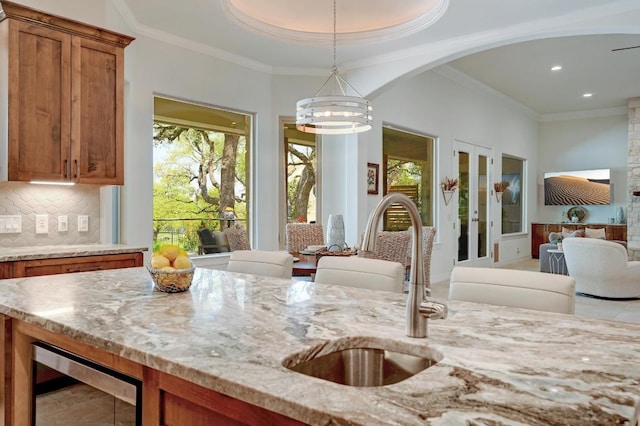290 Trailmaster Cir, Driftwood, TX 78619 - kitchen featuring wine cooler, brown cabinetry, healthy amount of natural light, open floor plan, and crown molding