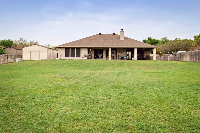 2129 Woodland Bend Rd, Salado, TX 76571 - rear view of house featuring a chimney, a fenced backyard, a shingled roof, an outdoor structure, and a yard