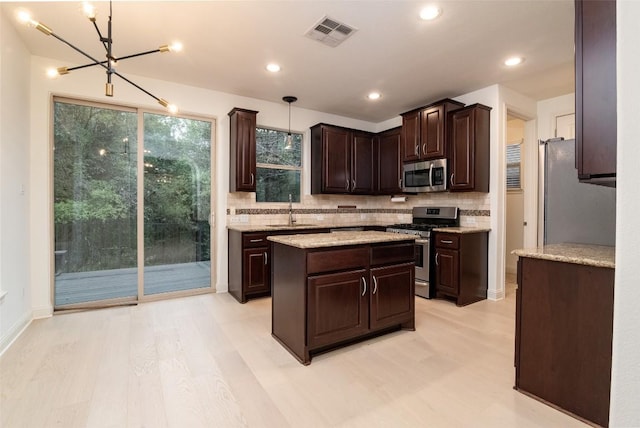 6108 Whipple Way, Austin, TX 78745 - kitchen with appliances with stainless steel finishes, a chandelier, decorative backsplash, dark brown cabinetry, and light wood-type flooring