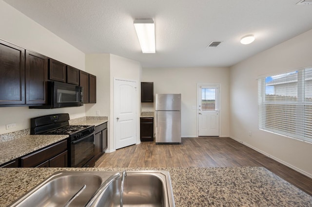 3603 Canaan Matthew Dr, Austin, TX 78725 - kitchen featuring black appliances, wood finished floors, and dark brown cabinets
