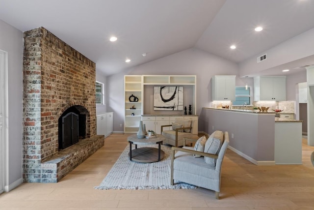 8702 Willowick Dr, Austin, TX 78759 - living room featuring light wood finished floors, a brick fireplace, lofted ceiling, and recessed lighting