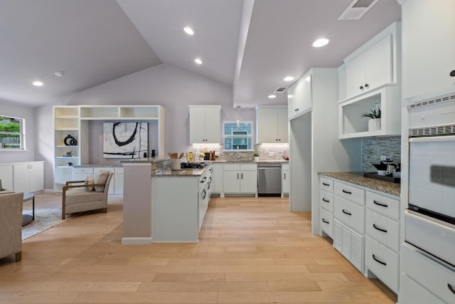 8702 Willowick Dr, Austin, TX 78759 - kitchen featuring stainless steel appliances, a warming drawer, decorative backsplash, light wood-style floors, and vaulted ceiling