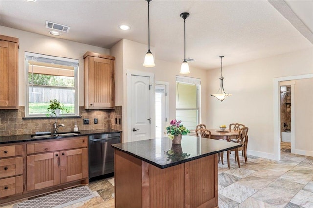 kitchen with visible vents, dishwasher, a kitchen island, tasteful backsplash, and a sink