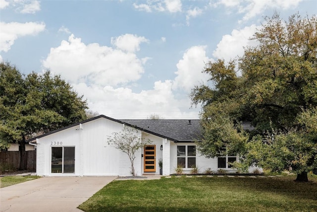 view of front of home with a shingled roof, fence, a front yard, and concrete driveway