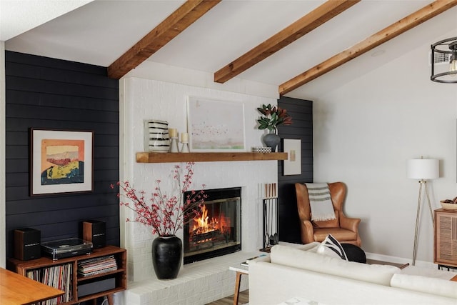 living room featuring a brick fireplace and beamed ceiling