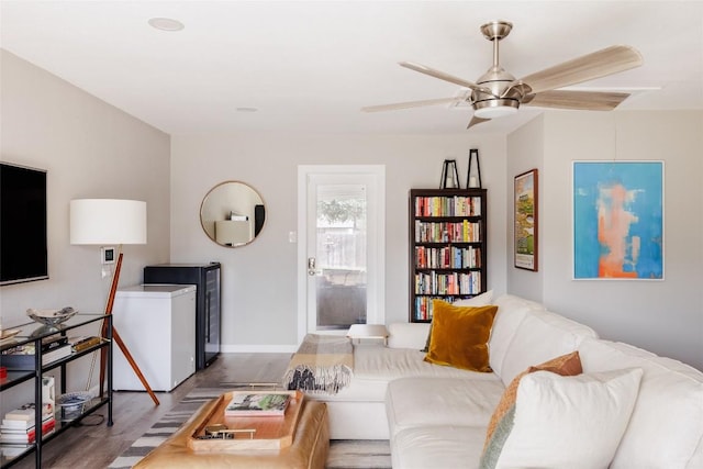 living room with baseboards, ceiling fan, and wood finished floors