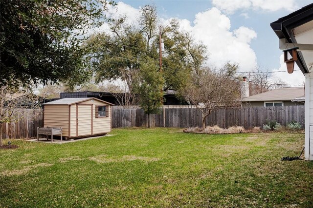 view of yard with a fenced backyard, an outbuilding, and a shed