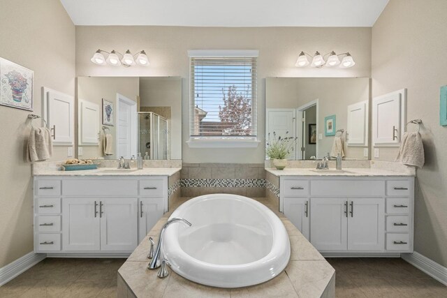 bathroom with a sink, baseboards, two vanities, a shower stall, and a bath