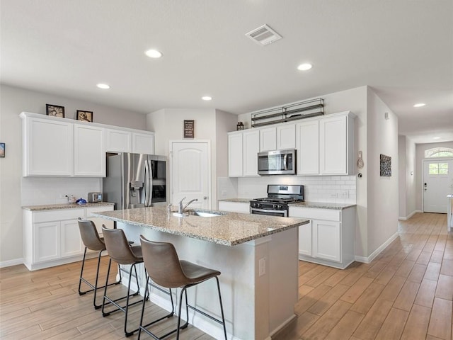 4104 Porter Farm Rd, Georgetown, TX 78628 - kitchen featuring tasteful backsplash, stainless steel appliances, a sink, visible vents, and light wood-style flooring