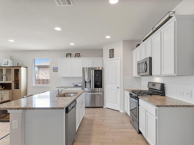 4104 Porter Farm Rd, Georgetown, TX 78628 - kitchen with appliances with stainless steel finishes, tasteful backsplash, white cabinetry, light wood-style floors, and recessed lighting