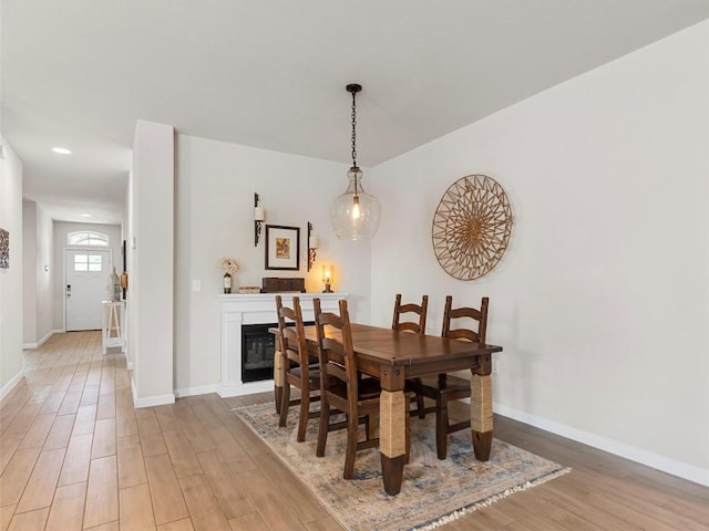 4104 Porter Farm Rd, Georgetown, TX 78628 - dining area with baseboards, light wood-style flooring, and a glass covered fireplace