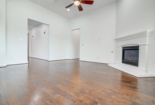 5617 Rio Chama Cv, Austin, TX 78738 - unfurnished living room with a ceiling fan, wood finished floors, baseboards, a fireplace with raised hearth, and a high ceiling