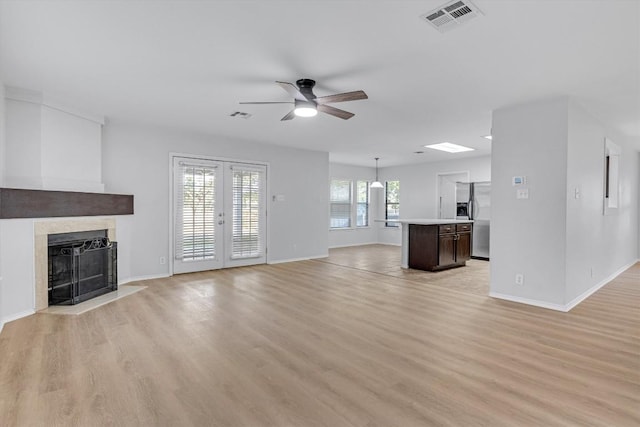 1434 Meadow Pkwy, San Marcos, TX 78666 - unfurnished living room featuring a fireplace with flush hearth, light wood-style floors, ceiling fan, and visible vents