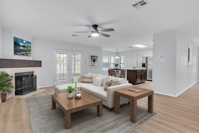 1434 Meadow Pkwy, San Marcos, TX 78666 - living room featuring a fireplace with flush hearth, visible vents, ceiling fan, and light wood-type flooring