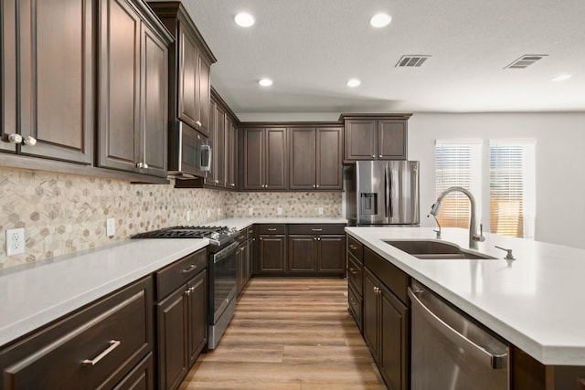 932 Azul Lagoon Dr Unit 18, Leander, TX 78641 - kitchen with stainless steel appliances, a sink, dark brown cabinets, light countertops, and recessed lighting