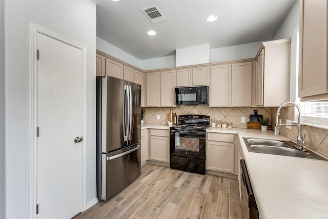 33 Verde Ranch Loop, Leander, TX 78641 - kitchen with black appliances, a sink, light countertops, backsplash, and light wood finished floors