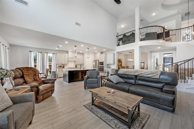 104 Trans Pecos Ct, Georgetown, TX 78628 - living room with a high ceiling, light wood finished floors, stairway, and a chandelier
