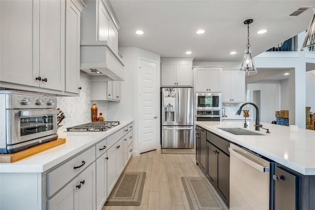 104 Trans Pecos Ct, Georgetown, TX 78628 - kitchen featuring appliances with stainless steel finishes, tasteful backsplash, light countertops, decorative light fixtures, and light wood-style floors