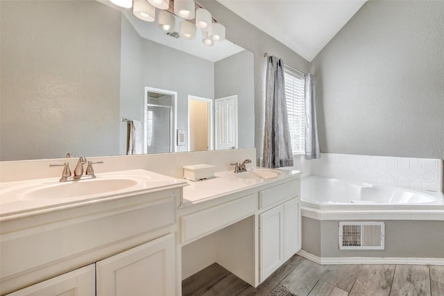 30003 Oakland Hills Dr, Georgetown, TX 78628 - full bathroom with double vanity, a garden tub, a stall shower, vaulted ceiling, and wood finished floors