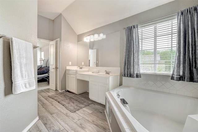 30003 Oakland Hills Dr, Georgetown, TX 78628 - bathroom featuring double vanity, vaulted ceiling, a bath, connected bathroom, and wood finished floors