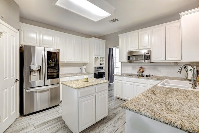 30003 Oakland Hills Dr, Georgetown, TX 78628 - kitchen featuring stainless steel appliances, white cabinetry, backsplash, and light wood-style flooring
