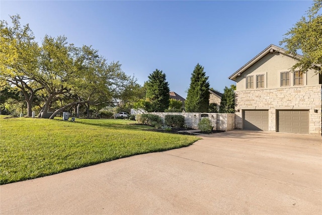 view of side of property featuring a yard, stone siding, a garage, concrete driveway, and stucco siding