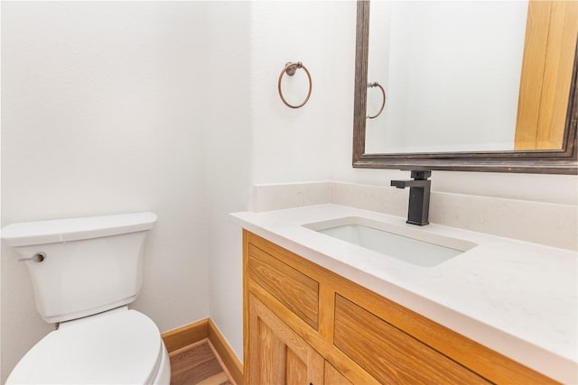 half bath featuring toilet, vanity, and baseboards