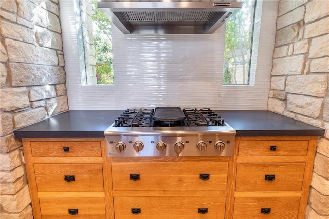 kitchen with dark countertops, wall chimney range hood, and stainless steel gas stovetop