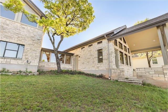 view of side of property with a yard and stone siding