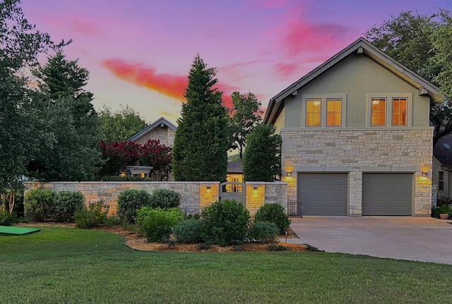 view of front of property with a yard, stone siding, fence, stucco siding, and driveway