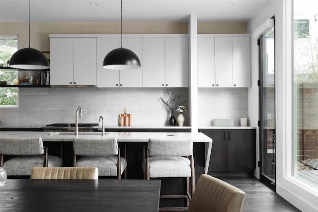 1105 W Monroe St, Austin, TX 78704 - kitchen featuring white cabinetry, decorative light fixtures, light countertops, a breakfast bar area, and backsplash