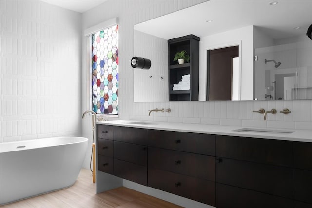 1105 W Monroe St, Austin, TX 78704 - bathroom featuring double vanity, a freestanding bath, wood finished floors, and decorative backsplash
