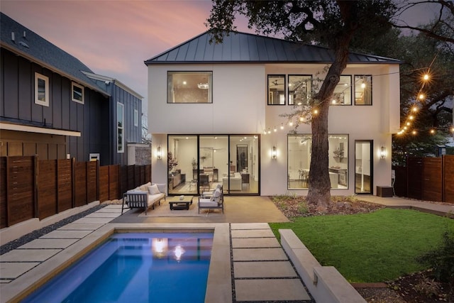 1105 W Monroe St, Austin, TX 78704 - back of house at dusk featuring a standing seam roof, an outdoor hangout area, stucco siding, a patio, and metal roof