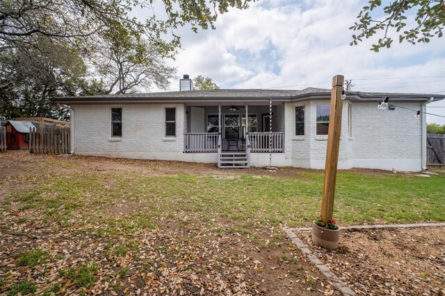 back of house featuring a chimney, fence, brick siding, ceiling fan, and a yard