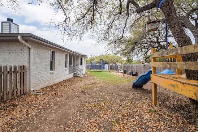 view of yard with a fenced backyard, a playground, and a trampoline