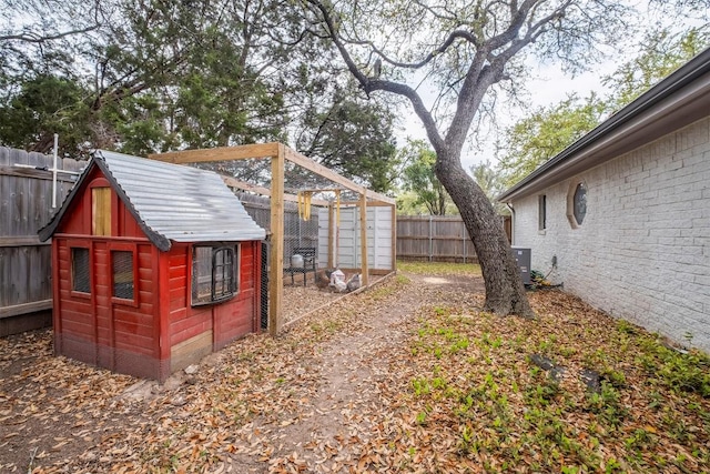 view of yard with exterior structure, an outbuilding, cooling unit, and a fenced backyard