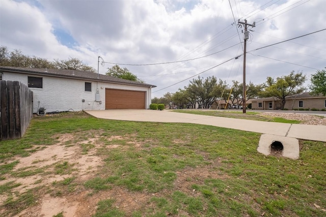 view of yard with an attached garage, driveway, and fence