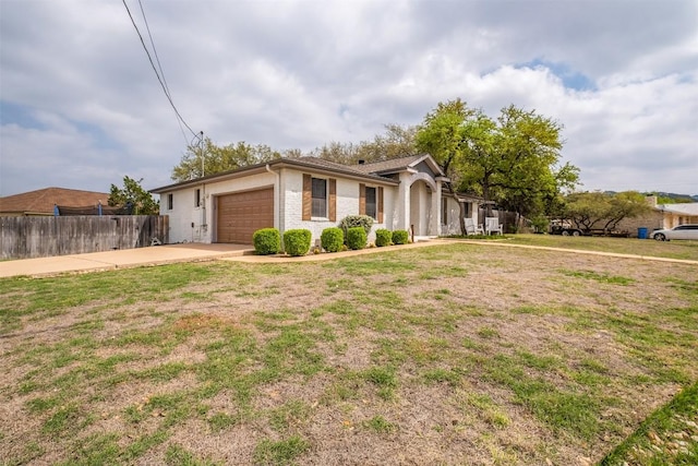 ranch-style house featuring an attached garage, driveway, a front lawn, and fence