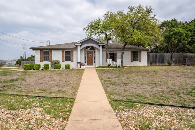 view of front facade with brick siding, fence, and a front yard