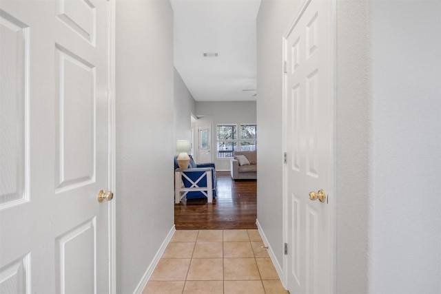 corridor with baseboards and light tile patterned floors