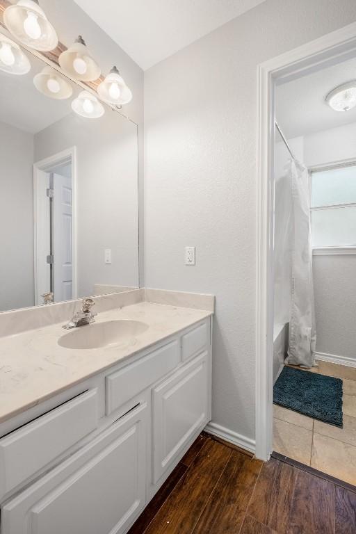 full bath with wood finished floors, vanity, and shower / bathtub combination with curtain