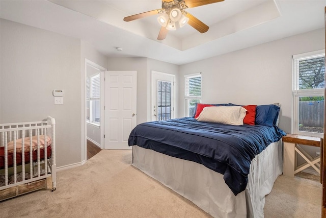 carpeted bedroom featuring baseboards, a ceiling fan, multiple windows, and a raised ceiling