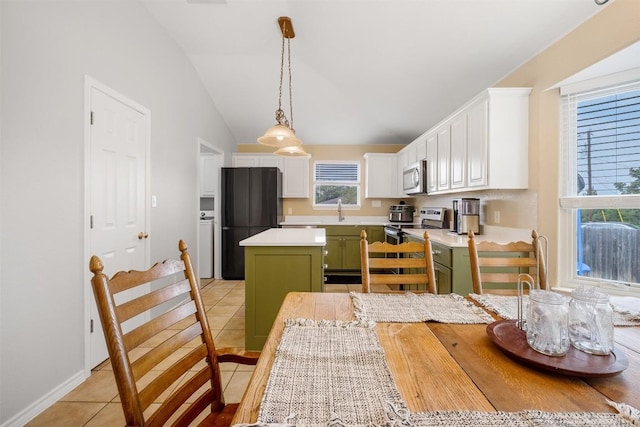 kitchen featuring white cabinets, green cabinetry, vaulted ceiling, light tile patterned flooring, and appliances with stainless steel finishes